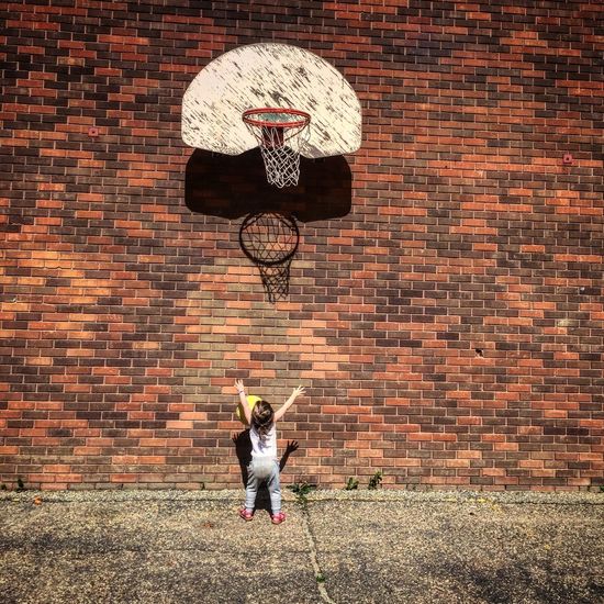 Full length of man standing against brick wall