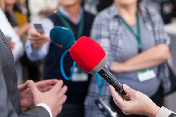 Cropped hand holding microphone while interviewing businessman