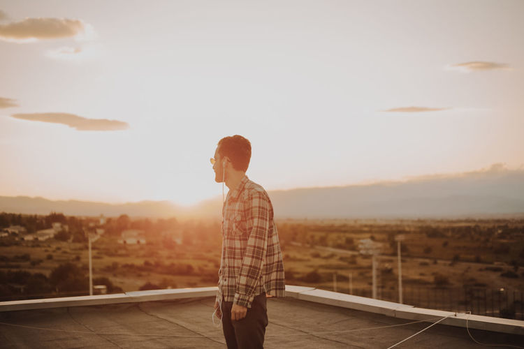 Man standing on terrace against sky during sunset