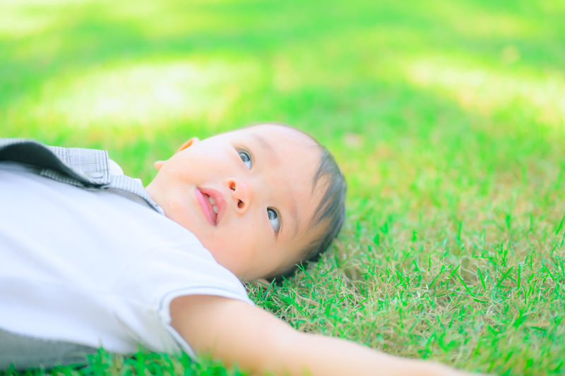 Portrait of cute boy lying on grassy field