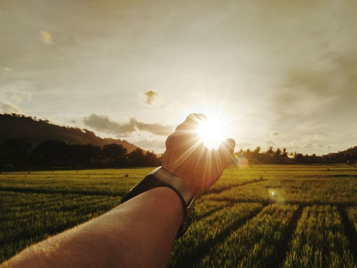 Hand holding sun shining over land