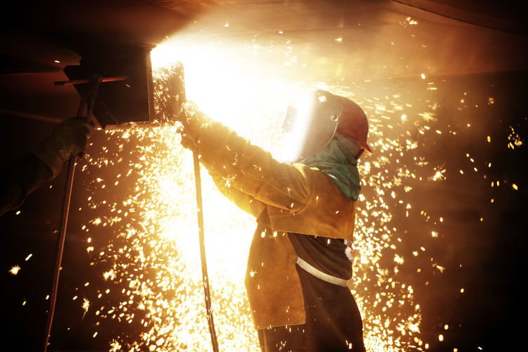 Side view of worker welding airplane wing at industry