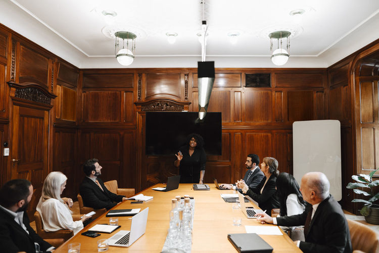 Businesswoman with multiracial colleagues discussing in board room during conference meeting