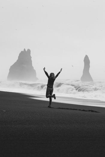 Excited tourist on empty black beach monochrome scenic photography