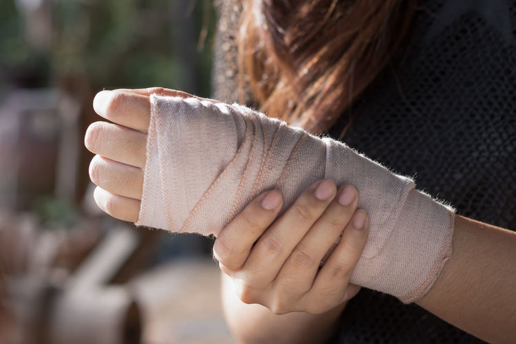 Midsection of woman with wrapped bandage on hand