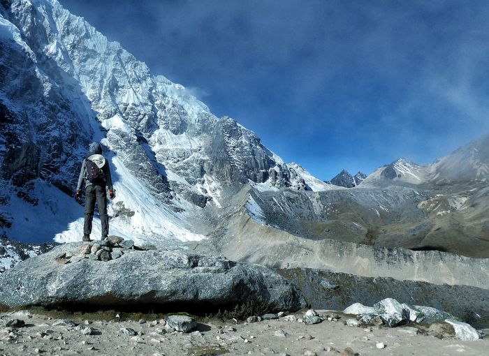 Rear view of man overlooking snowcapped rocky mountains