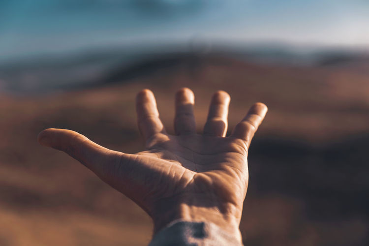 Close-up of human hand against sky