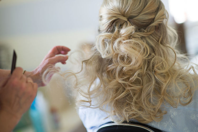 Cropped image of hairdresser styling customer hair in salon