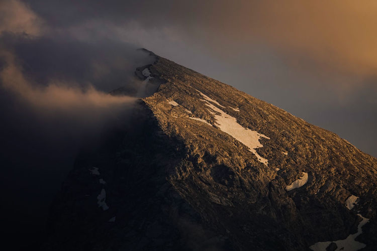 Snowcapped mountain against cloudy sky during sunset