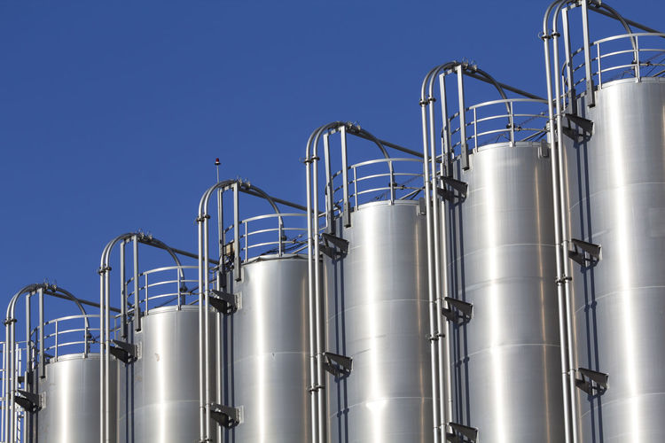 Low angle view of industry against clear blue sky