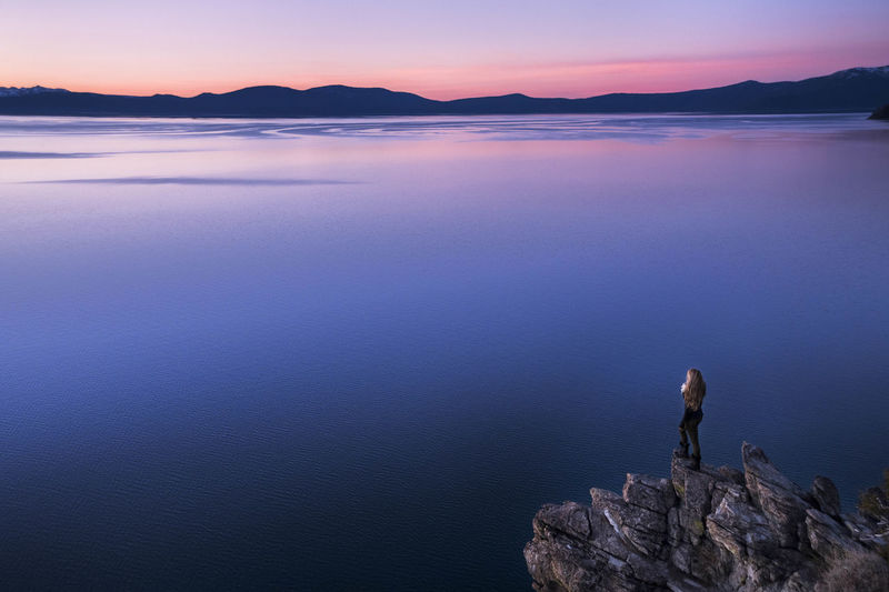 Woman looking at view while standing on rock formation by lake tahoe during sunset