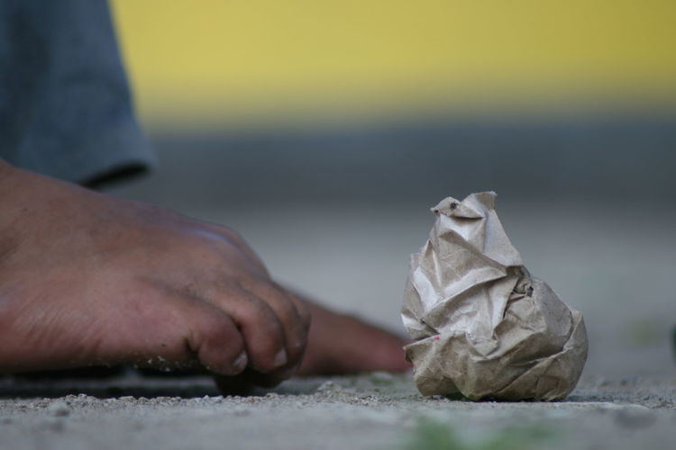 Close-up of human foot by crumpled paper on land
