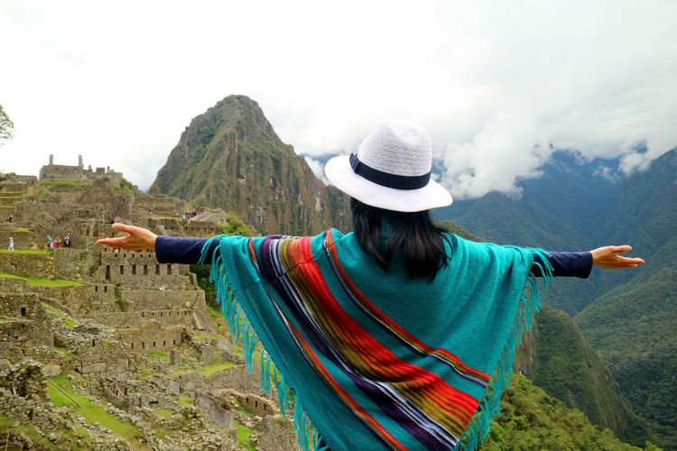 Rear view of woman standing by mountain against sky
