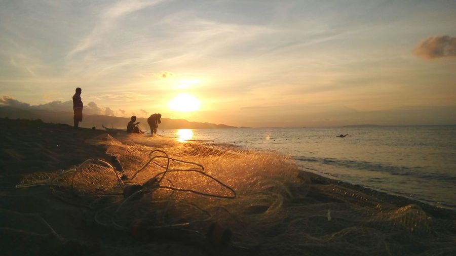 Fishing net at beach against sky during sunset