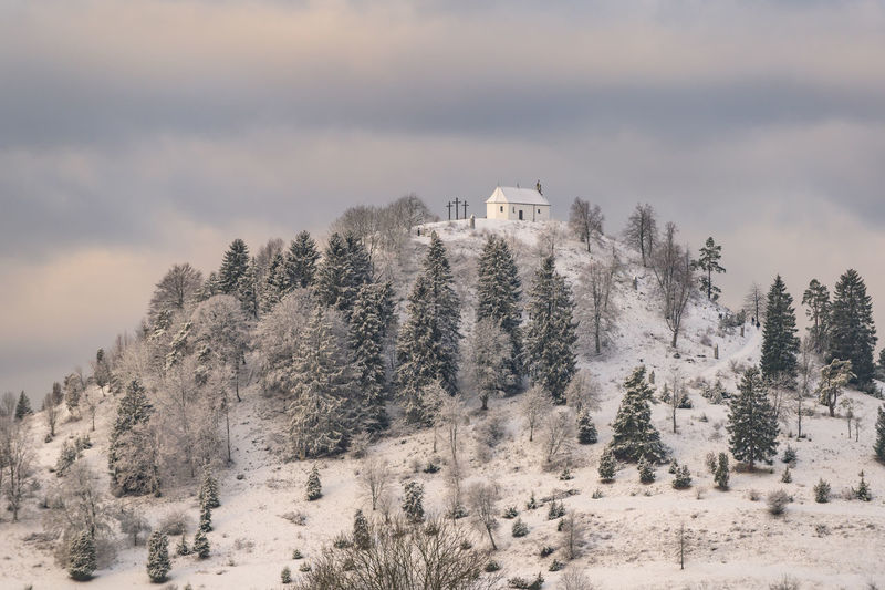 Snow covered hill with trees and chappel on top located on swabian alb