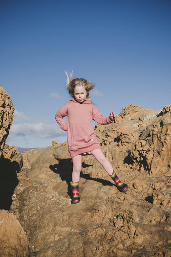 Portrait of girl standing on rock against sky