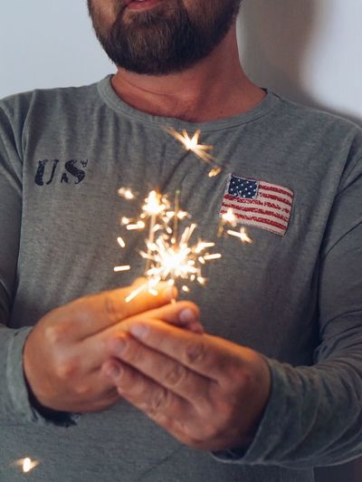 Midsection of man holding illuminated sparkler