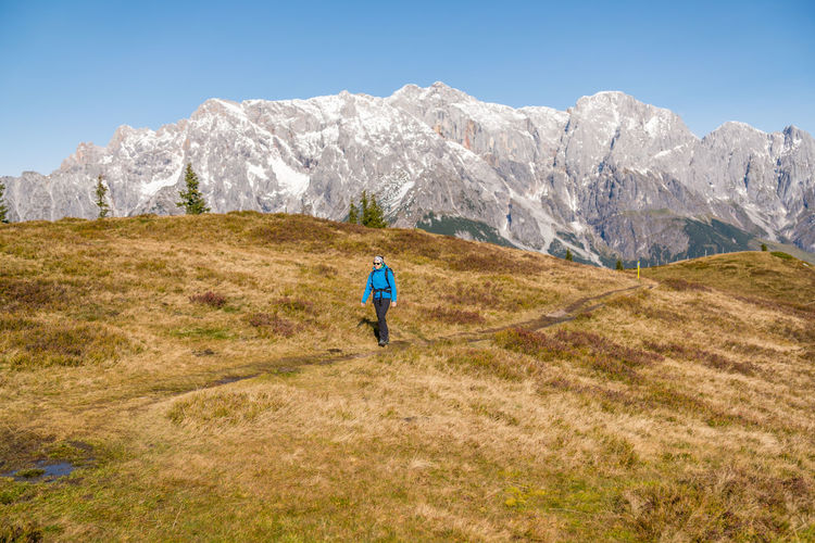 Woman hiking on footpath in alpine landscape, hochkönig, austria.