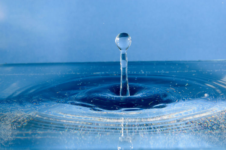Close-up of drop splashing on blue water