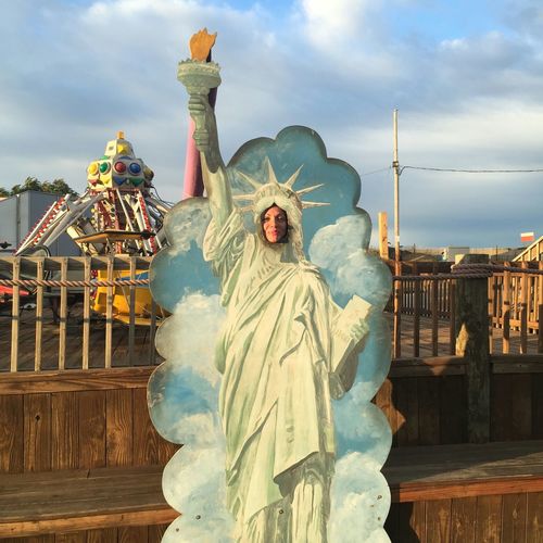 Woman behind statue of liberty replica at amusement park