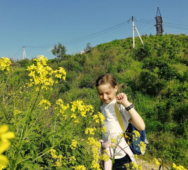 Full length of girl with yellow flowers on field