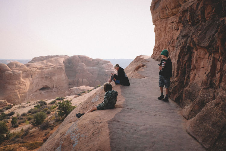 Three boys checking their cell phones during a hike in the desert.
