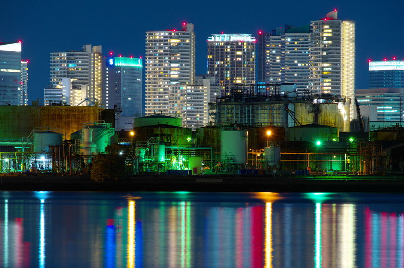 Illuminated buildings by river in city at night