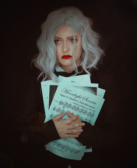 Sad woman holding musical note against black background