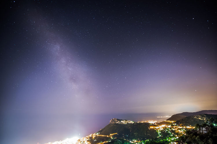 Aerial view of illuminated city on mountain against sky at night