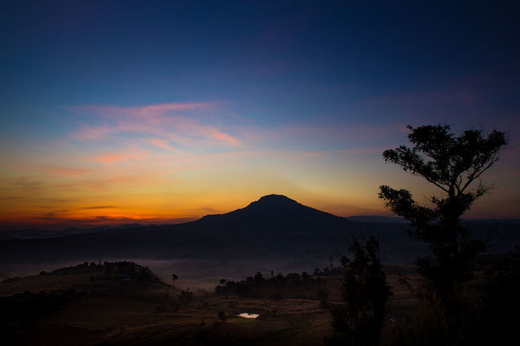 Scenic view of silhouette mountains against orange sky