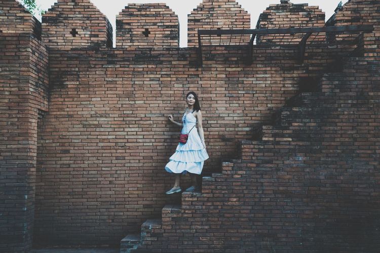 Full length of woman on brick wall