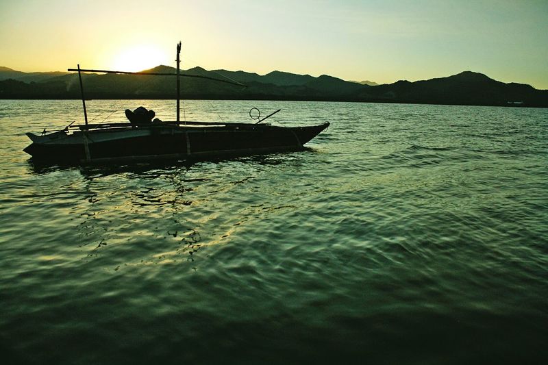 Boats in sea at sunset