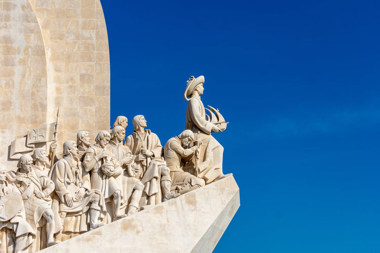 Closeup of statues on monument to the discoveries on blue sky, lisbon