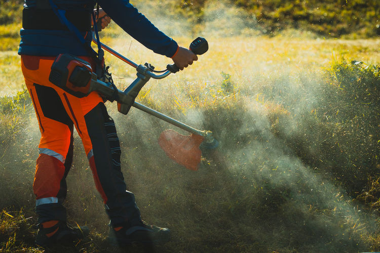 Low section of man sprinkling fertilizers while standing on field