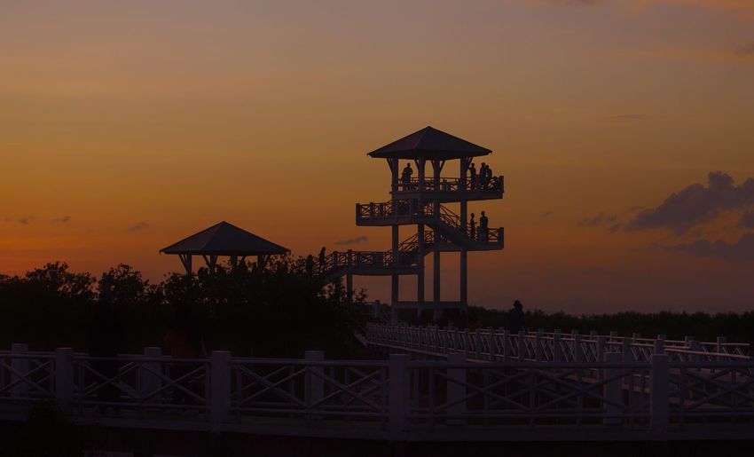Silhouette built structure by sea against sky during sunset