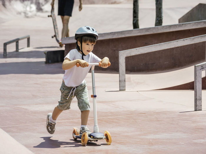 Full length of boy skateboarding on street