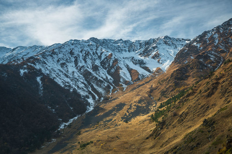 Snow on mountain tops in autumn. scenic view of snowcapped mountains against sky