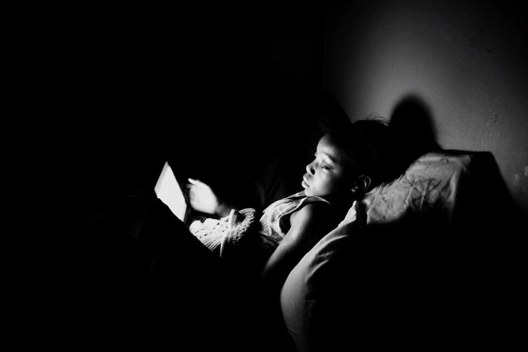 Girl using digital tablet while lying down on bed at home