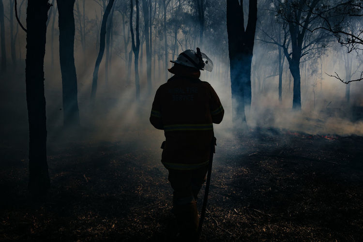 Firefighter in a forest with a hose during fighting a large wildfire