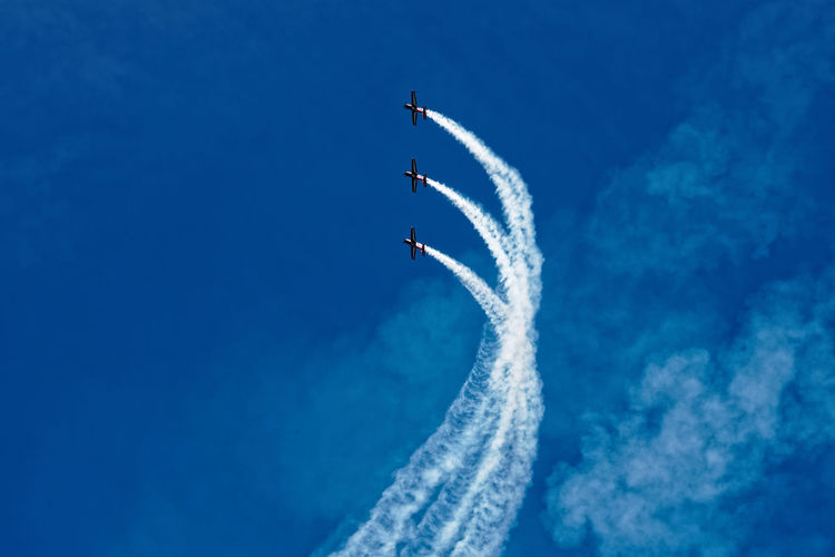 Low angle view of airplane flying against clear blue sky