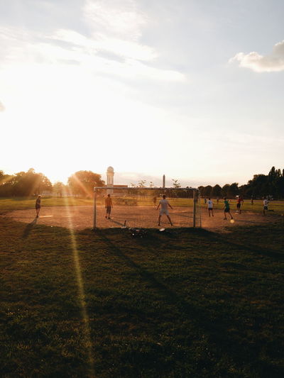 People playing soccer on field against sky