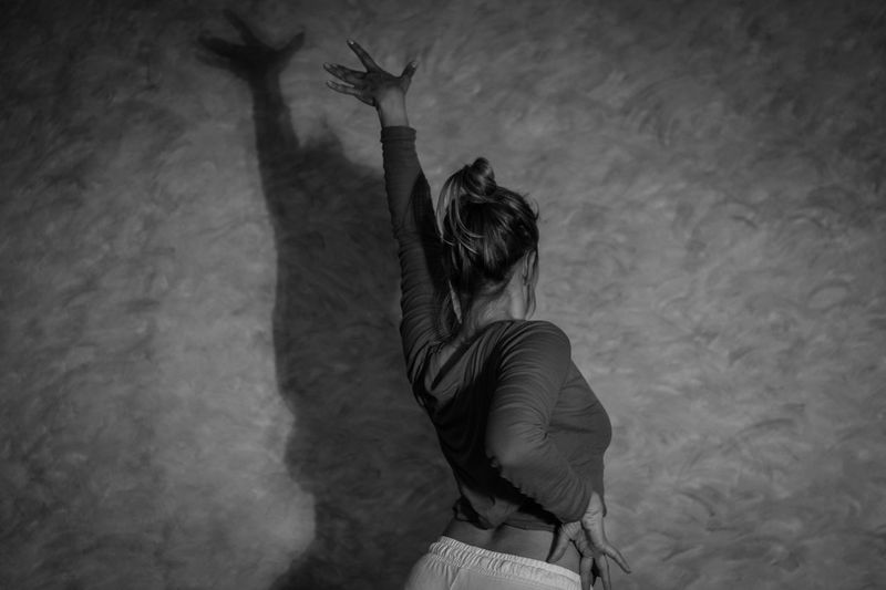 Rear view of woman dancing against shadow on wall