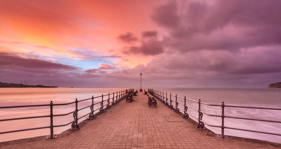 Pier over sea against sky during sunset