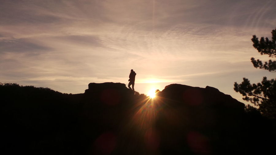 Silhouette man standing on landscape at sunset