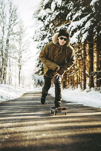 Full length of man skateboarding on road by snow