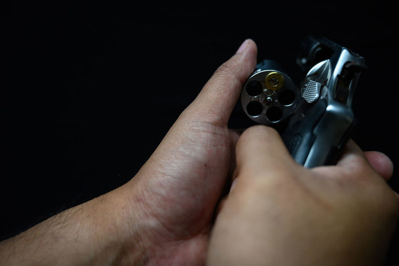 Close-up of hand holding camera over black background