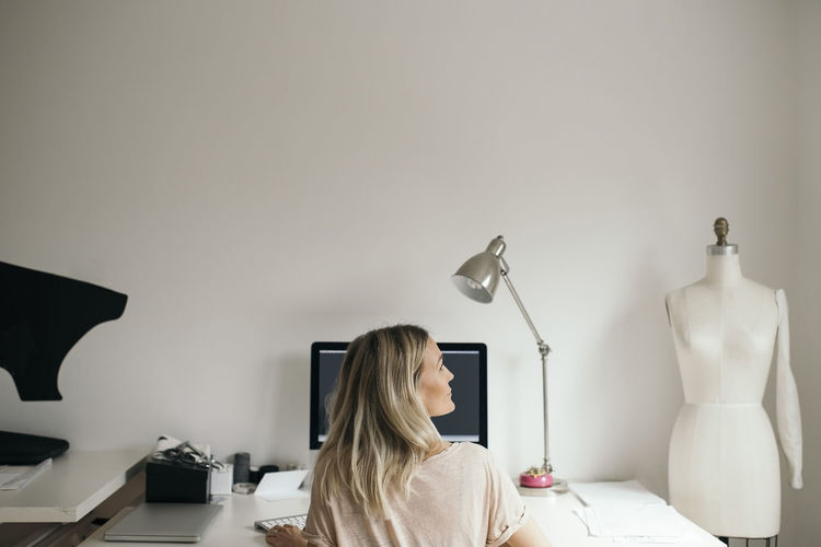 Rear view of female design professional using computer at home