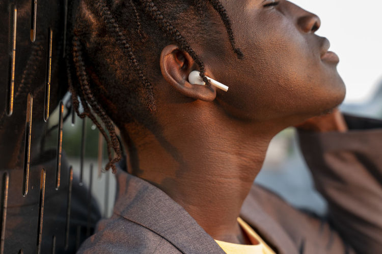 Young businessman listening to music through wireless in-ear headphones