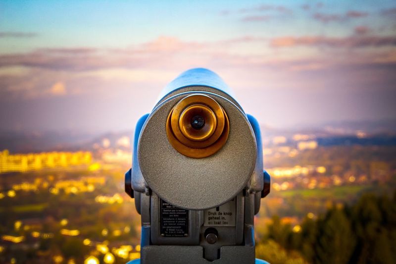Close-up of coin-operated binoculars against sky during sunset