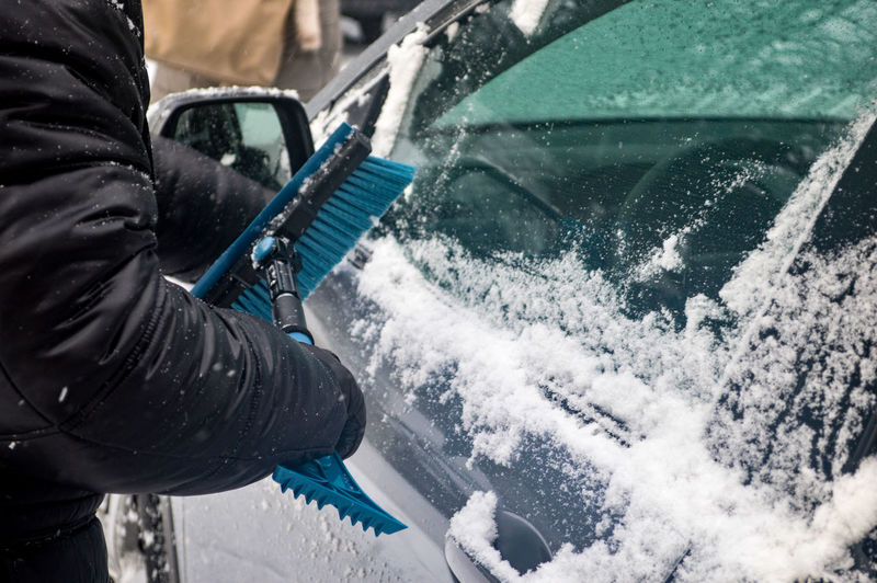 Person removing snow on car